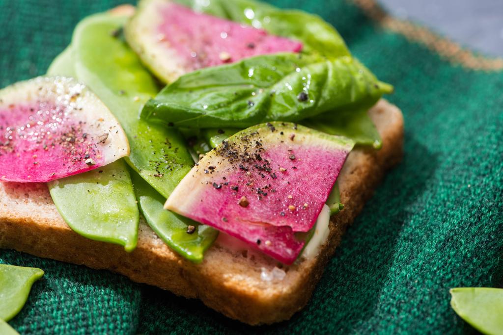Nahaufnahme von Toast mit Rettich, grünen Erbsen und Basilikum auf Tuch - Foto, Bild