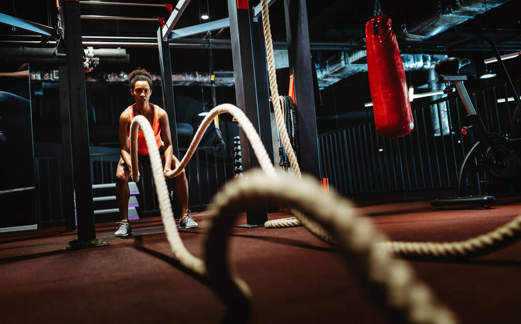 Fit woman working out with battle ropes at a gym - Photo, Image
