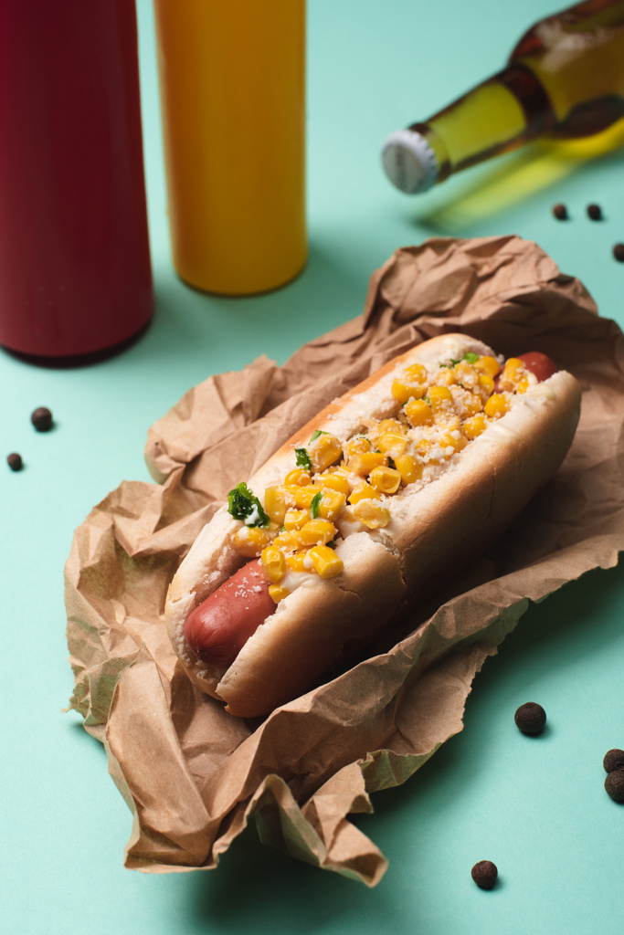 hot dog con maíz y botellas con cerveza, mostaza y ketchup en azul
 - Foto, Imagen