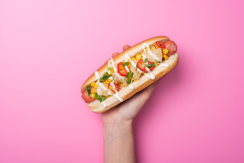 vista ritagliata della donna che tiene delizioso hot dog su rosa
 - Foto, immagini