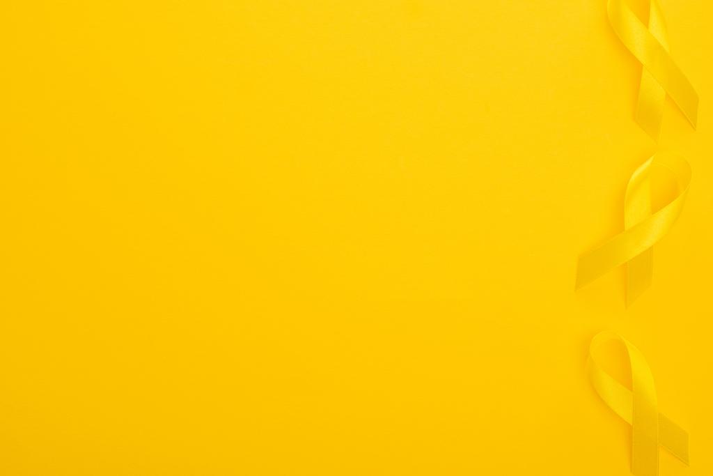 Parlak arkaplanda sarı kurdeleler, uluslararası çocukluk kanseri günü konsepti. - Fotoğraf, Görsel
