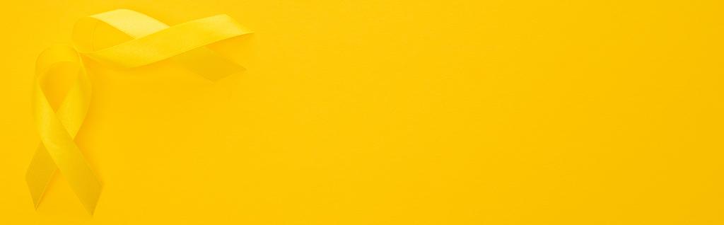カラフルな背景に黄色のリボンのトップビュー,パノラマ撮影,国際小児がんの日の概念 - 写真・画像