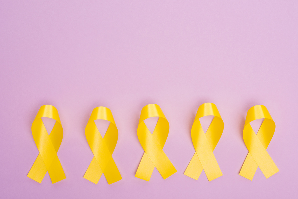 Acostado plano con cintas de conciencia amarillas en violeta, concepto del día internacional del cáncer infantil
 - Foto, imagen