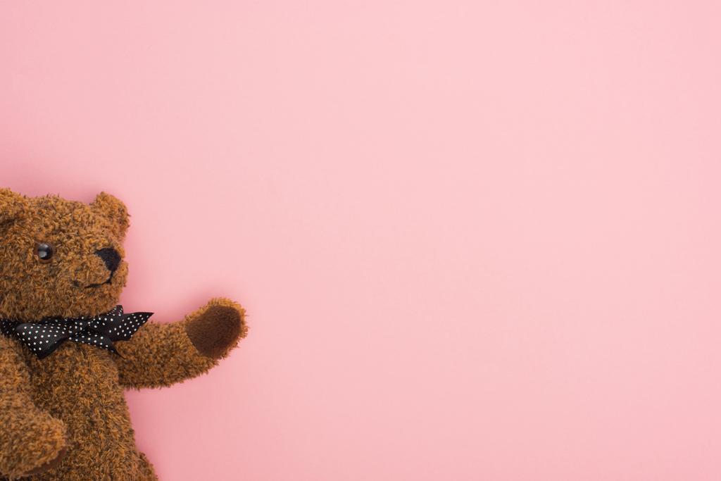Vista superior del osito de peluche marrón con lazo sobre fondo rosa
 - Foto, imagen