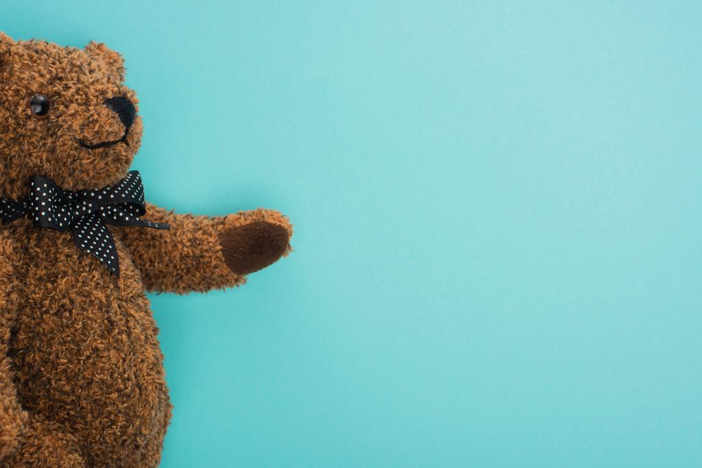 Top view of brown teddy bear with bow on blue background - Photo, Image