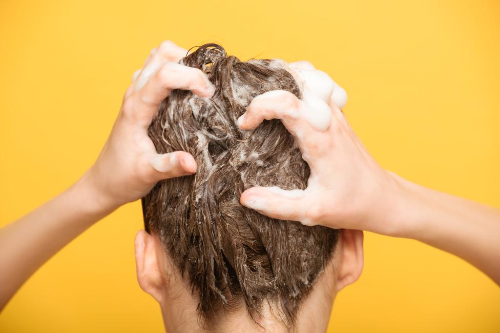 visão traseira da mulher lavar o cabelo com shampoo isolado no amarelo
 - Foto, Imagem