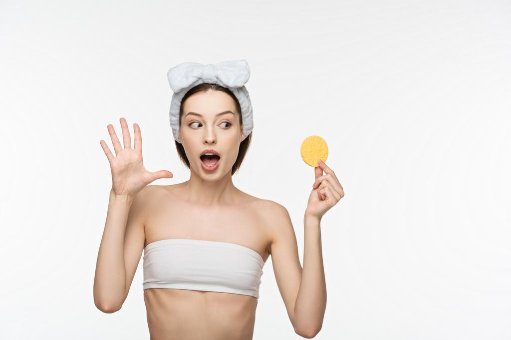 excitada chica mostrando wow gesto mientras sostiene esponja cosmética aislado en blanco
 - Foto, imagen