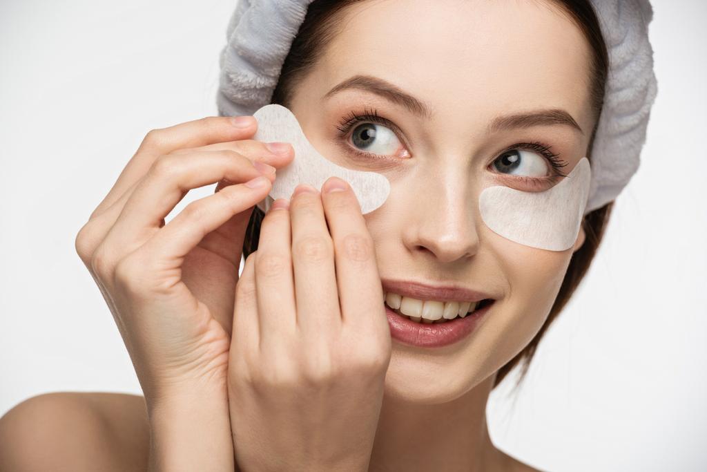 beautiful, smiling girl applying eye patch isolated on white  - Photo, Image