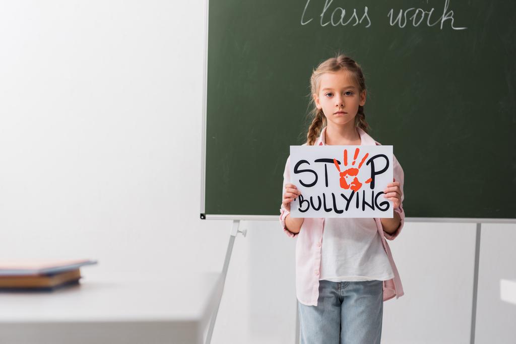enfoque selectivo de colegiales que sostienen pancarta con letras de stop bullying
  - Foto, Imagen