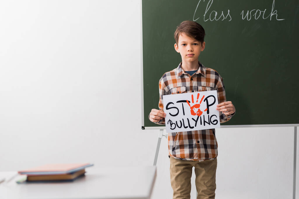 教室でのいじめをやめさせるプラカードを持つ少年の選択的焦点 - 写真・画像