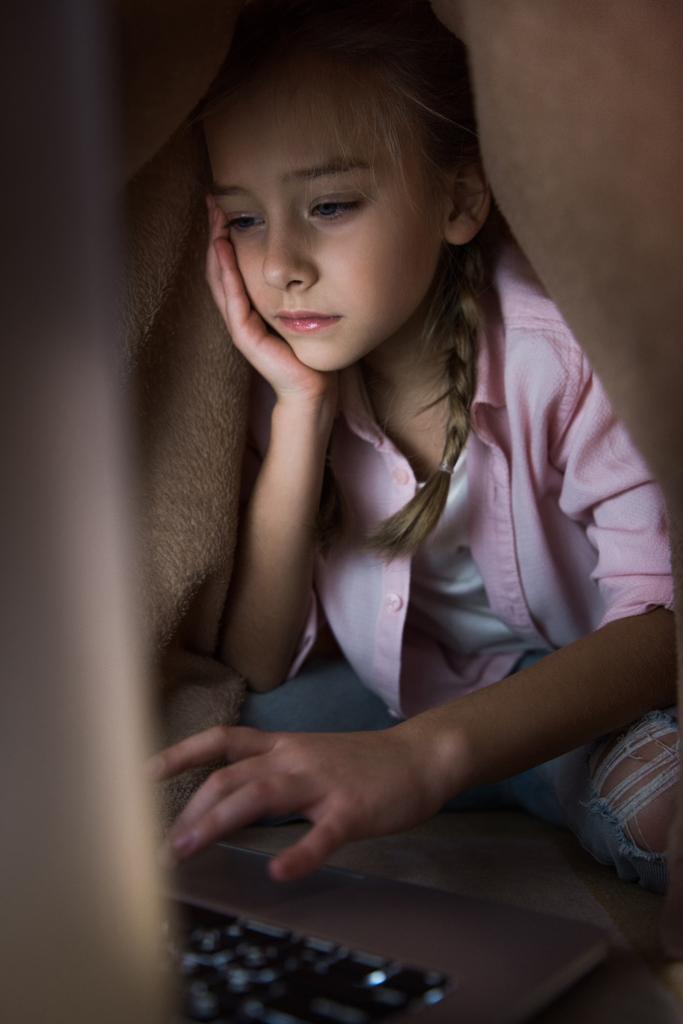 selective focus of frustrated kid covered in blanket using laptop, cyberbullying concept  - Photo, Image