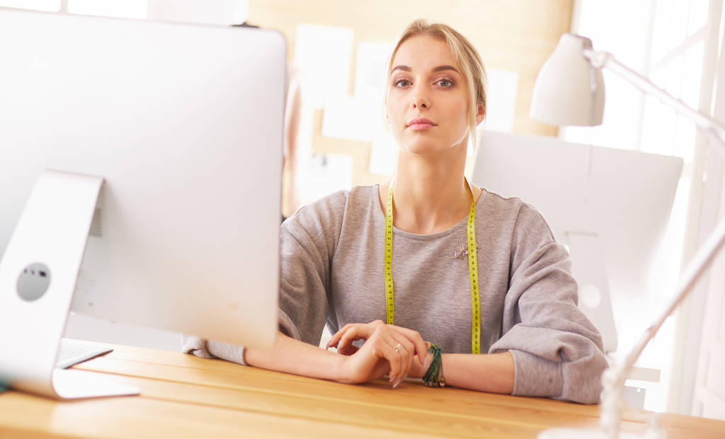 Γυναίκα σχεδιάστρια μόδας που εργάζεται στο στούντιο, κάθεται στο γραφείο - Φωτογραφία, εικόνα