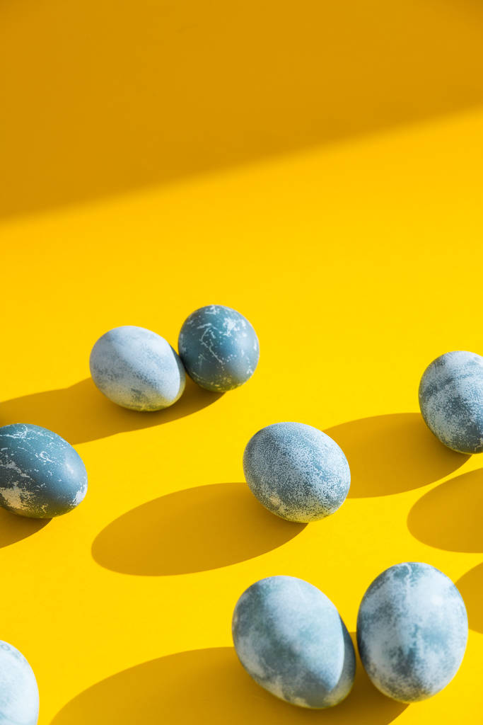 Blue textured colored Easter eggs on a bright yellow holiday background backdrop. Spring holiday concept. Copyspace. Flat lay. Top view. - Photo, Image
