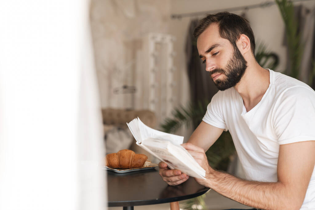 Hombre en el interior de casa tienen un libro de lectura de desayuno
. - Foto, imagen
