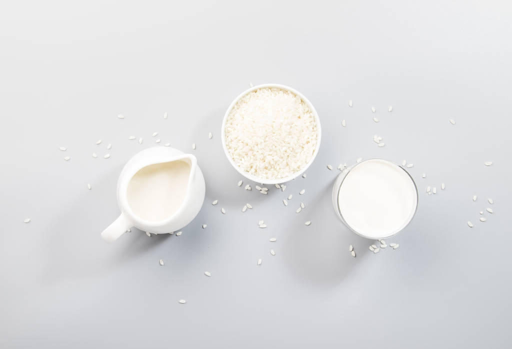 Veganistische rijstmelk op basis van melk in flessen, close-up, grijze achtergrond. Alternatieve melk voor niet-zuivel. Gezond vegetarisch eten en drinken concept. Kopieer ruimte, bovenaanzicht - Foto, afbeelding