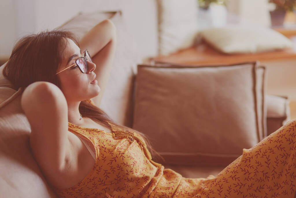 Mujer relajada sentada en un sofá moderno en casa - Foto, imagen