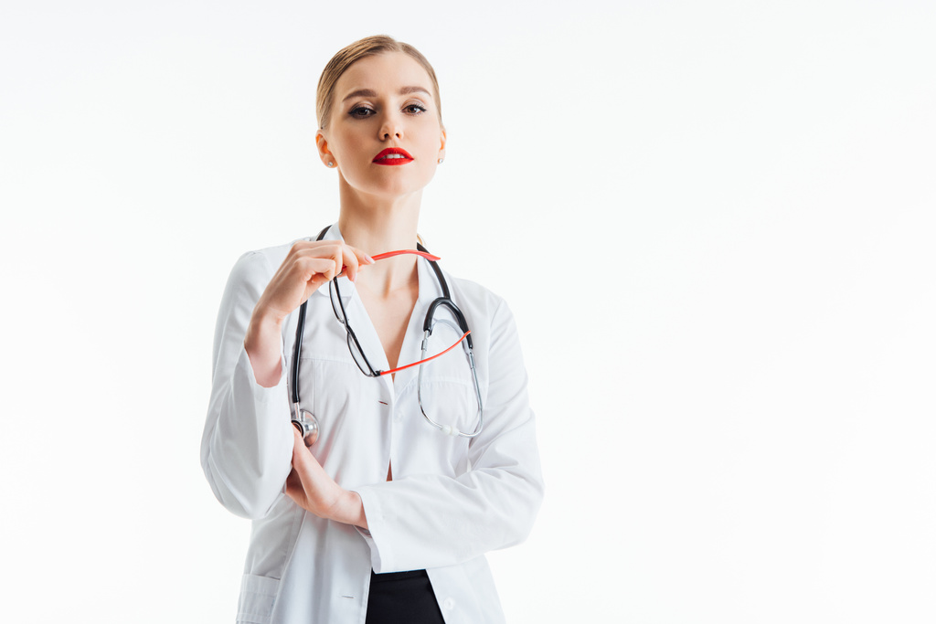 sexy nurse holding glasses and looking at camera isolated on white  - Photo, Image