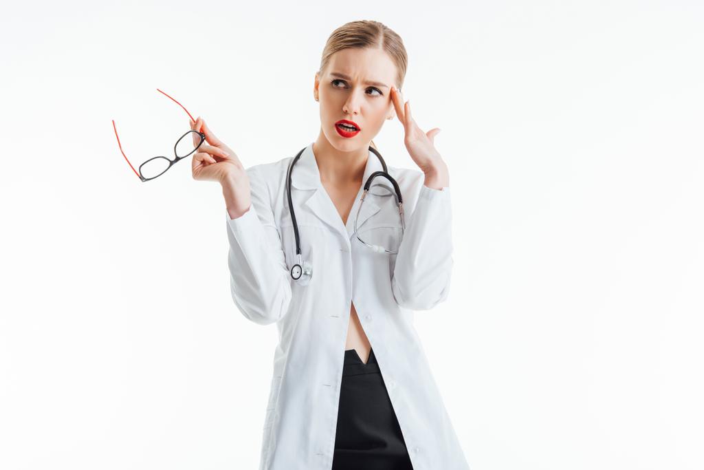 pensive sexy verpleegster holding bril en weg te kijken geïsoleerd op wit  - Foto, afbeelding