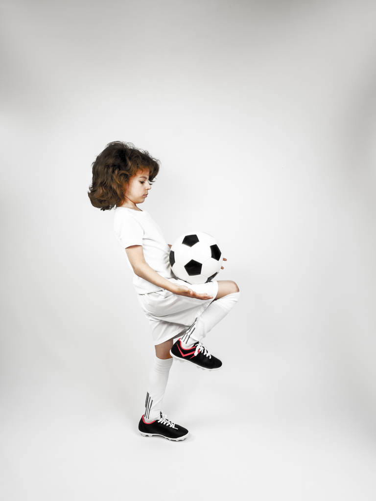Piłkarz żonglujący piłką z kolanem na szarym tle - Zdjęcie, obraz