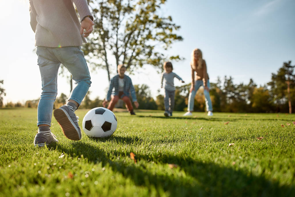 サッカーの準備はできていますか?。幸せな家族は草原でボールで遊んでいます - 写真・画像