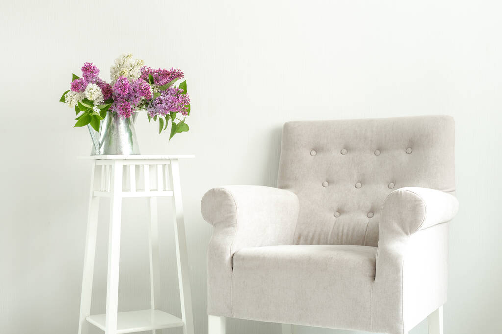 Un sillón acogedor y un ramo de lilas. Un lugar para leer o una taza de café. Acogedor interior escandinavo. Minimalismo - Imagen
 - Foto, imagen