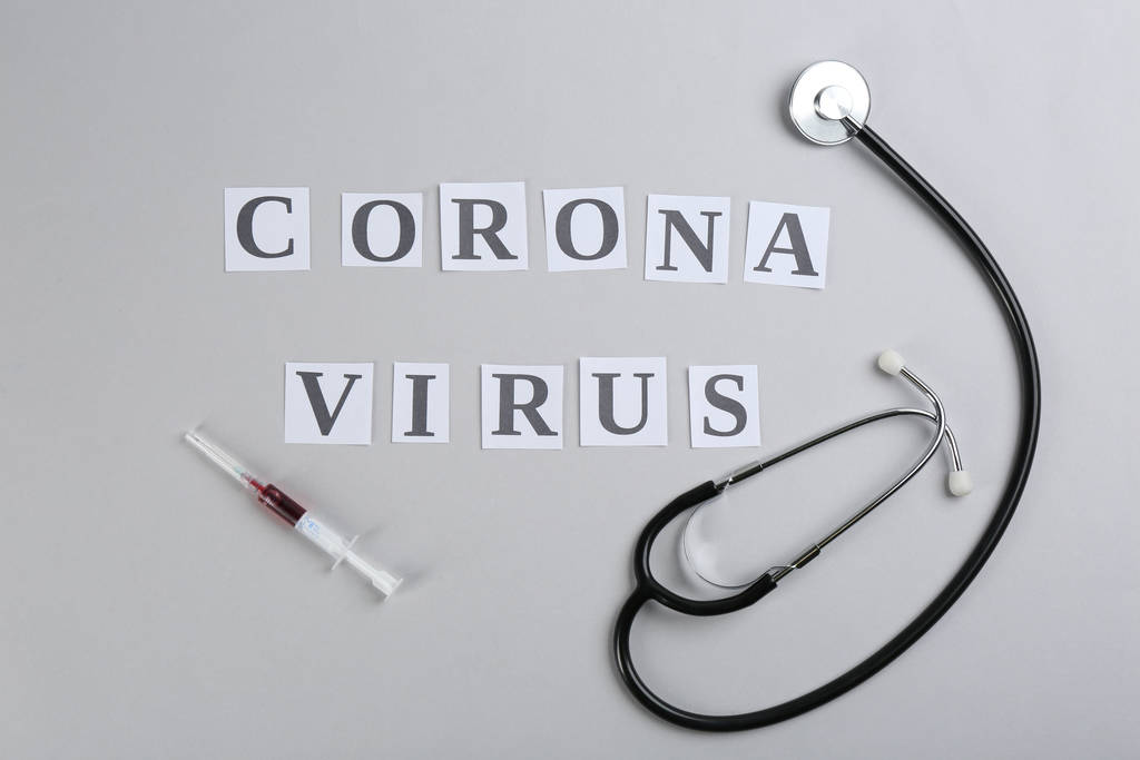 Плоская композиция со словами CORONA VIRUS, стетоскоп и шприц на светло-сером фоне
 - Фото, изображение