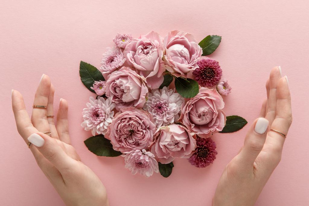 vista superior de flores florecientes de primavera y manos femeninas sobre fondo rosa
 - Foto, Imagen