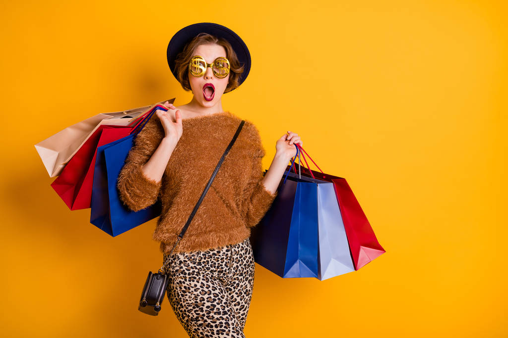 Photo of crazy lady open mouth szezon értékesítési bevásárlóközpont hordoznak sok csomag viselni bolyhos pulóver leopárd nadrág retro sapka válltáska hűvös arany szemüveg elszigetelt sárga szín háttér - Fotó, kép
