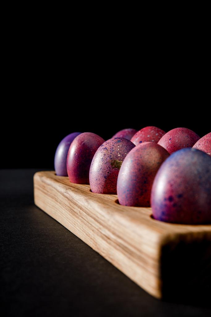 Selective focus of Easter eggs on wooden board on grey and black background - Photo, Image
