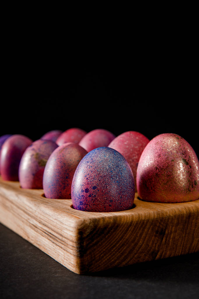 Επιλεκτική εστίαση των αυγών του Πάσχα σε ξύλινη σανίδα σε μαύρο - Φωτογραφία, εικόνα