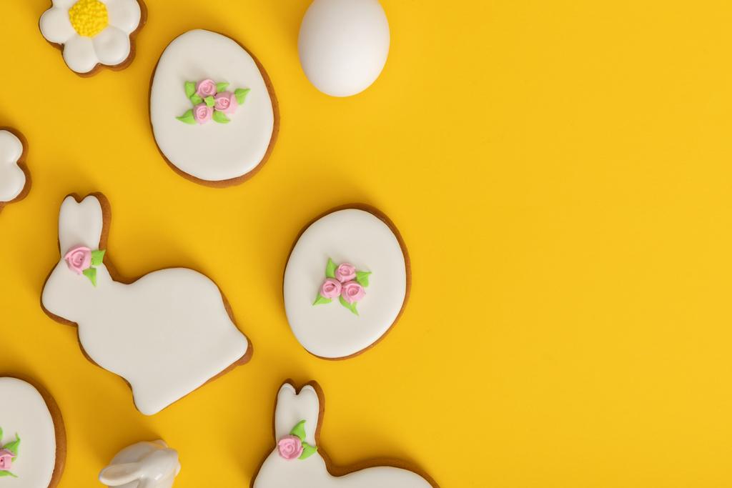 Vista superior de huevo de gallina, galletas y conejito decorativo sobre fondo amarillo
 - Foto, imagen