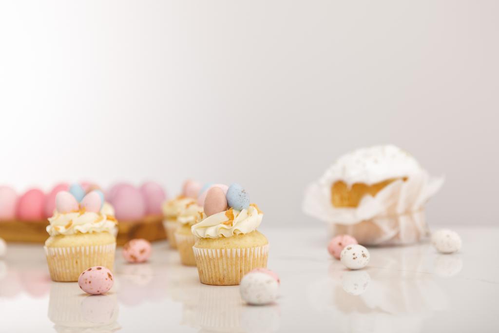Enfoque selectivo de cupcakes con pollo pintado y huevos de codorniz cerca de pastel de Pascua sobre fondo gris
 - Foto, imagen