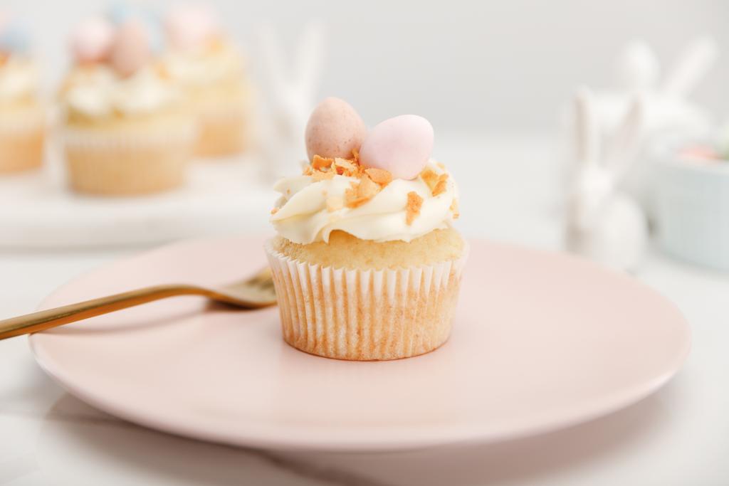 Selectieve focus van cupcake op plaat met vork op grijze achtergrond - Foto, afbeelding