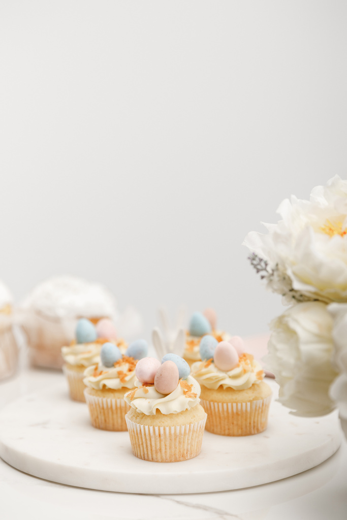 Concentration sélective de cupcakes sur carton rond avec des fleurs sur fond gris
 - Photo, image