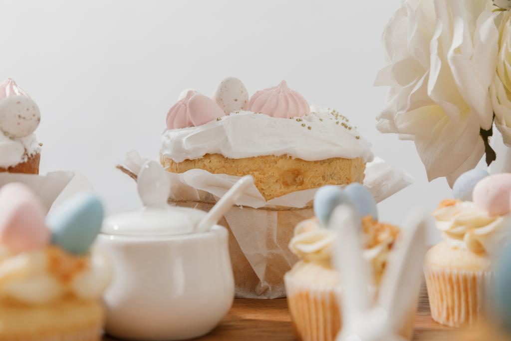 Selective focus of cupcakes, sugar bowl, Easter bread and flowers isolated on grey - Foto, Bild