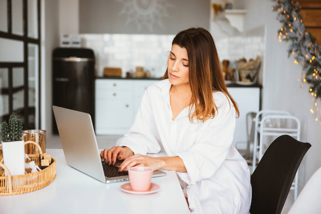 Счастливая красивая женщина в белой рубашке работает на ноутбуке
. - Фото, изображение
