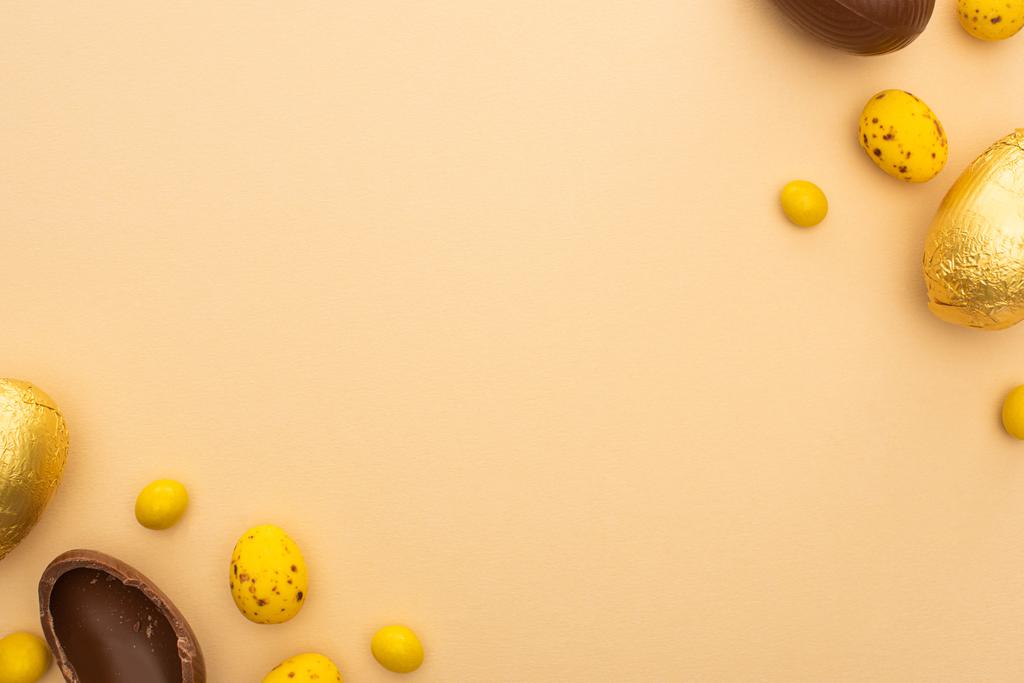 Vista superior de huevos de chocolate y codorniz con caramelos amarillos en beige
 - Foto, imagen