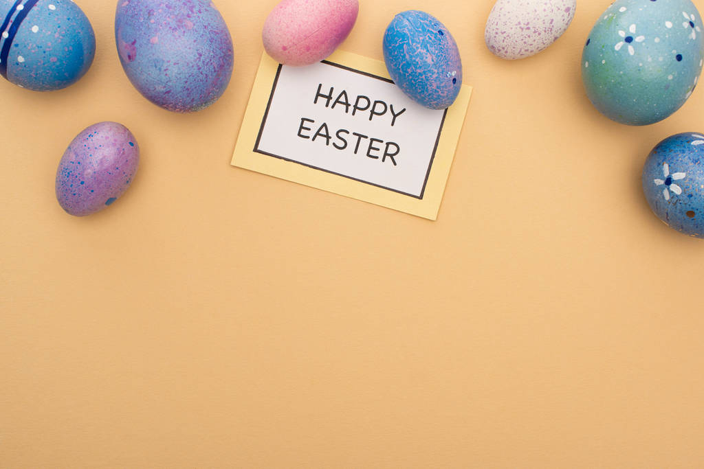 Vista superior de la tarjeta con letras de Pascua feliz y huevos de Pascua sobre fondo beige
 - Foto, Imagen