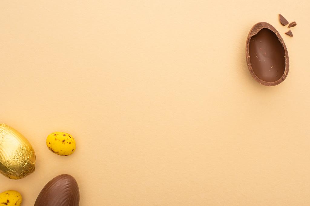 Top view of yellow quail and chocolate easter eggs on beige background - Photo, Image