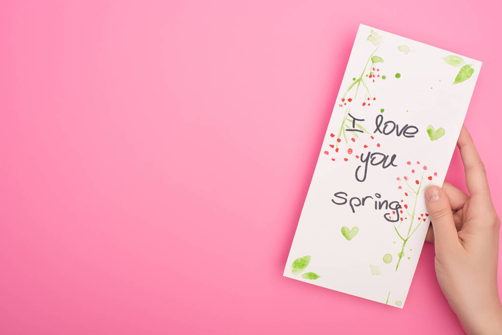 Vue partielle de la carte avec je t'aime lettrage de printemps dans la main de la femme sur fond rose
 - Photo, image