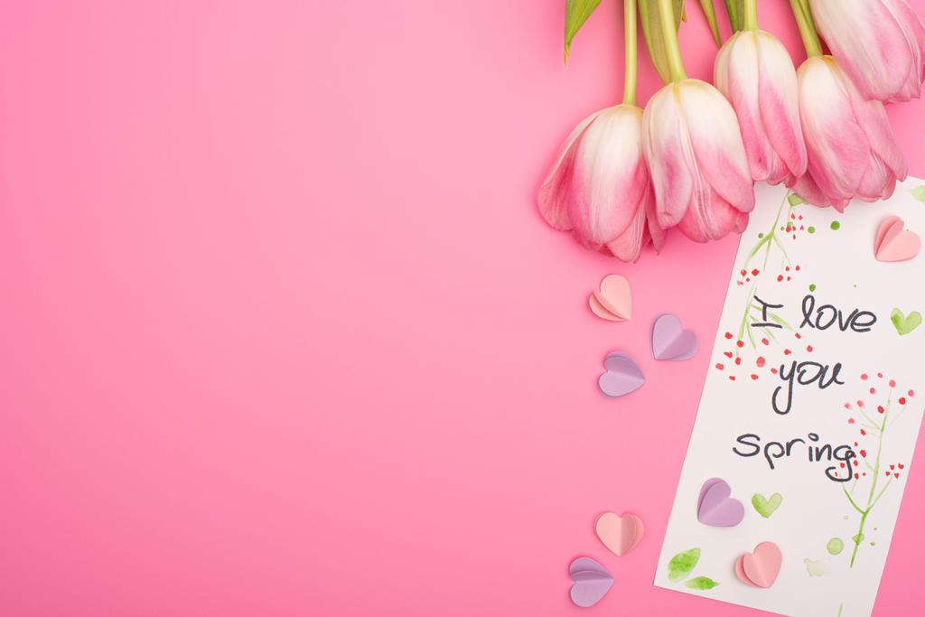 Bovenaanzicht van tulpen, kaart met ik hou van je lente belettering en kleurrijke decoratieve harten op roze achtergrond - Foto, afbeelding