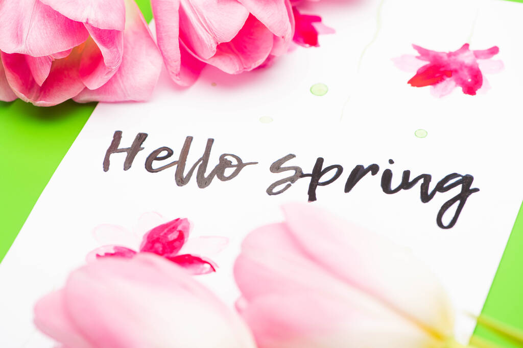 Selektivní zaměření růžových tulipánů a karet s nápisem Hello Spring na zeleném pozadí - Fotografie, Obrázek