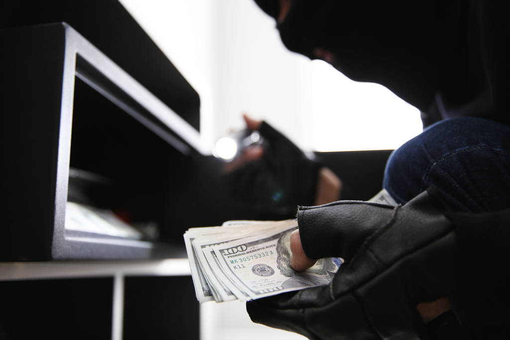 Ladrón sacando dinero de la caja fuerte de acero en el interior, primer plano
 - Foto, imagen