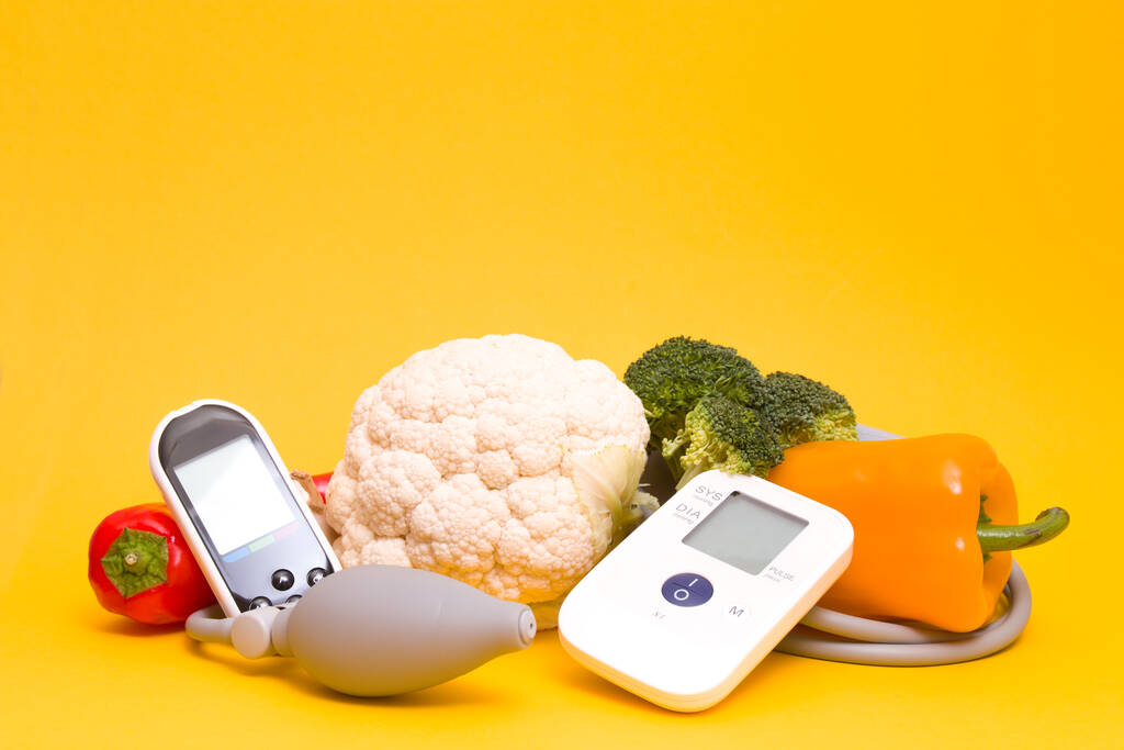 tonometro e misuratore di glucosio su fondo giallo, invece di una copia, un mazzo di verdure fresche, un corretto concetto di alimentazione, abbassamento dello zucchero nel sangue, pressione cardiaca, concetto di diabete
 - Foto, immagini