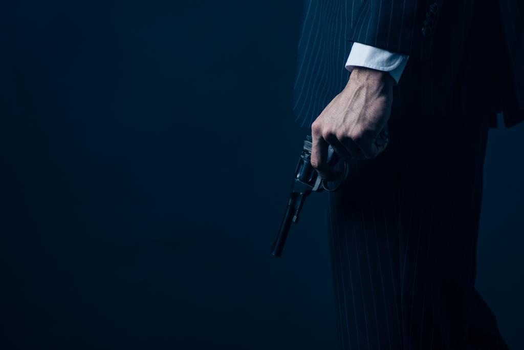 Vista ritagliata di gangster pistola in mano su sfondo scuro
 - Foto, immagini