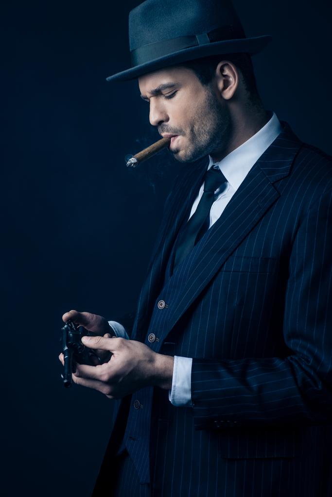 Gangster com charuto na boca carregando revólver em azul escuro
 - Foto, Imagem