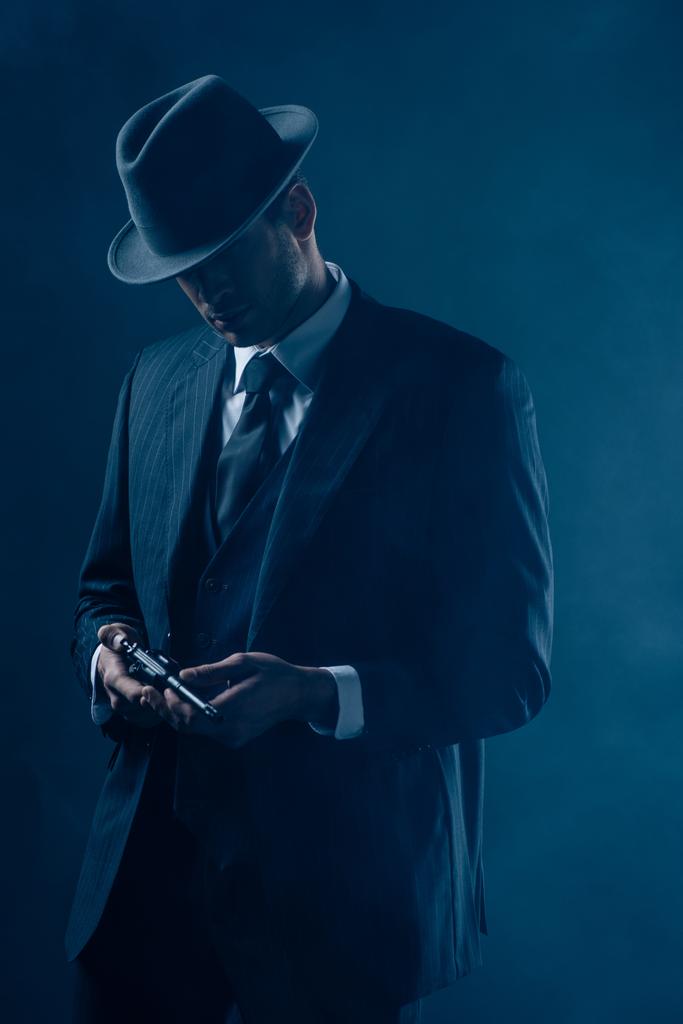 Gangster mit Revolver in der Hand auf dunkelblauem Hintergrund - Foto, Bild