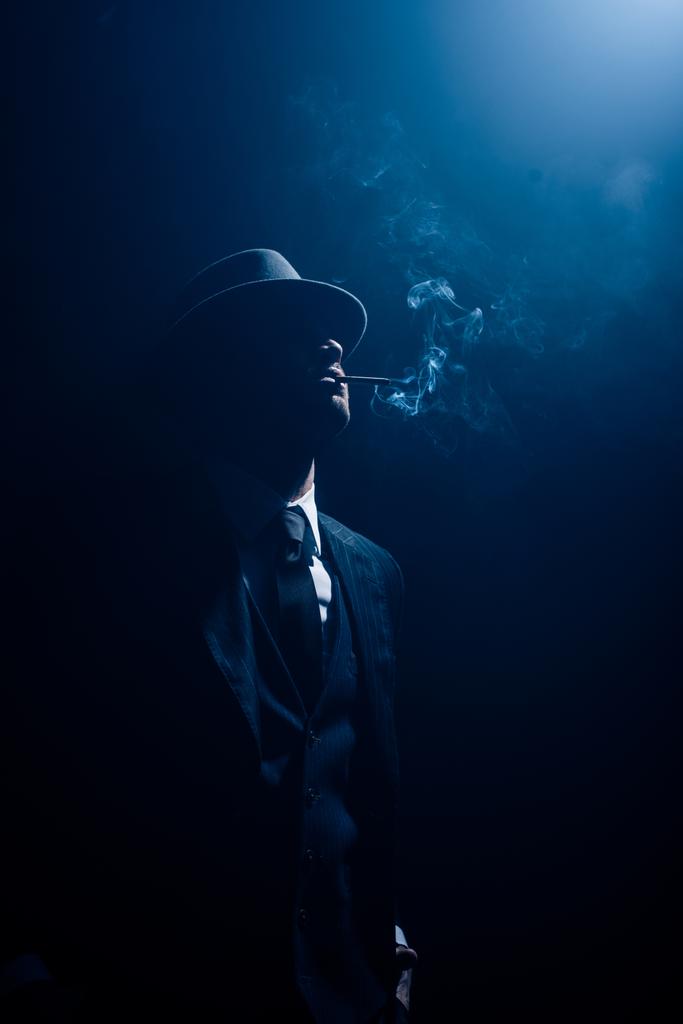 Silhouette di mafioso fumare sigaretta su sfondo blu scuro
 - Foto, immagini