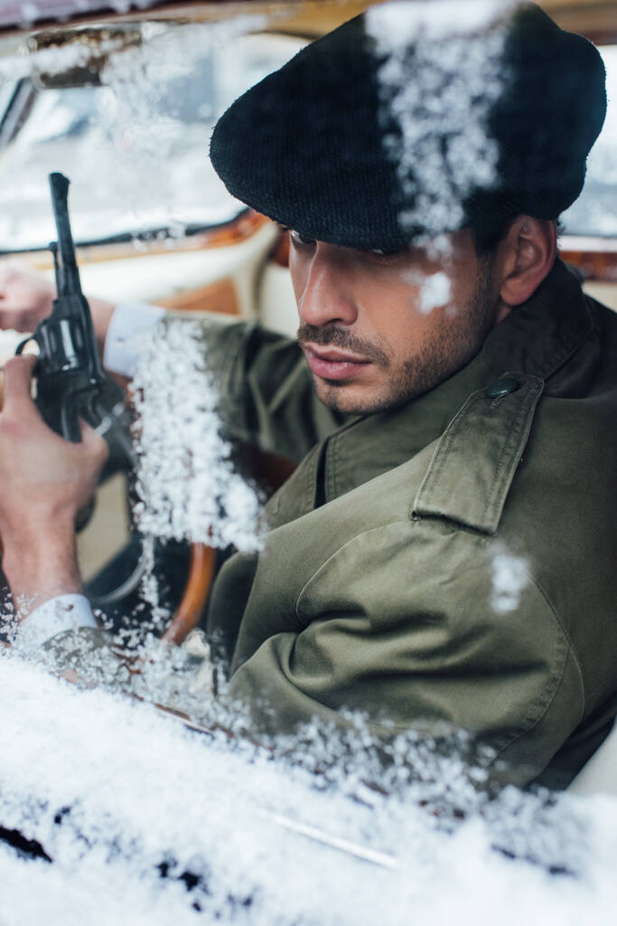 Выборочный фокус мафиози с пистолетом в машине, покрытой снегом
 - Фото, изображение