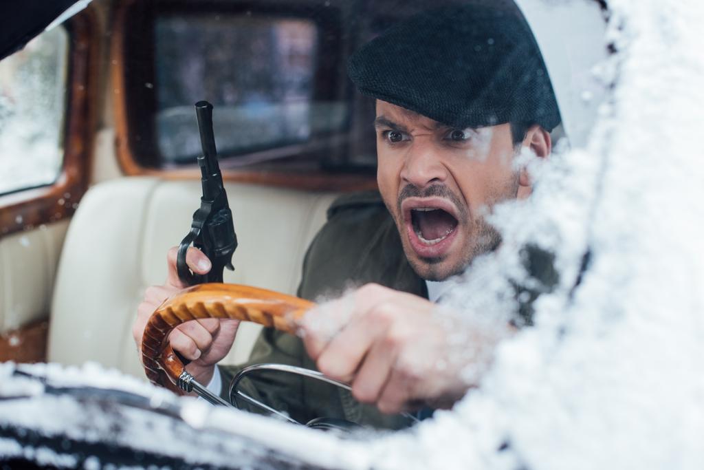 Szelektív fókusz dühös gengszter fegyver vezetés autó - Fotó, kép